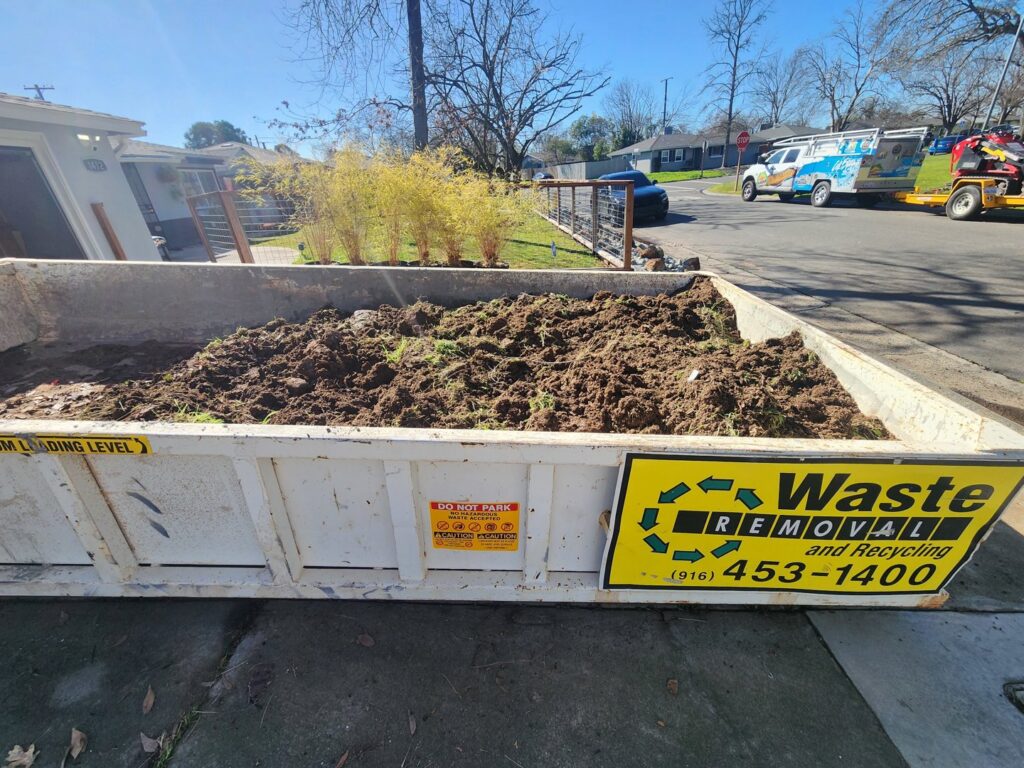 A roll-off dumpster filled with organic yard waste and soil for removal by Waste Removal and Recycling in Sacramento, CA.