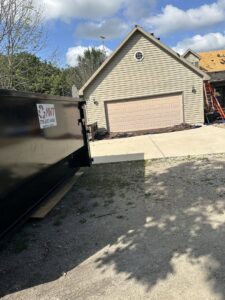 An MWT Dumpster and Hauling Services dumpster placed on a driveway for construction debris removal at a home in Morris, IL.