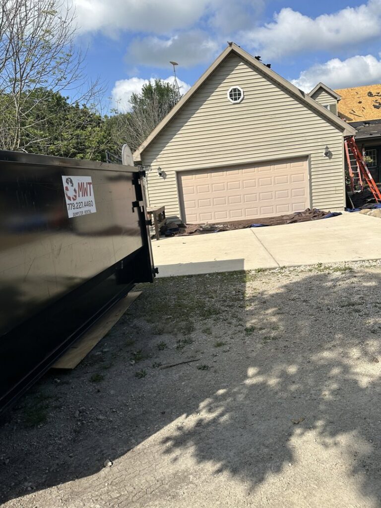 An MWT Dumpster and Hauling Services dumpster placed on a driveway for construction debris removal at a home in Morris, IL.