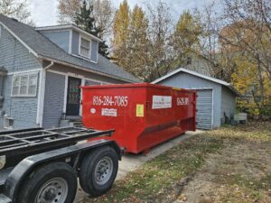 A red dumpster from Trinity Dumpster Rental LLC ready for junk removal at a residential property in Kansas City, MO.