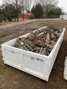A dumpster filled with concrete blocks and various construction debris, managed by Standard Waste Enterprises in Greenville, SC.