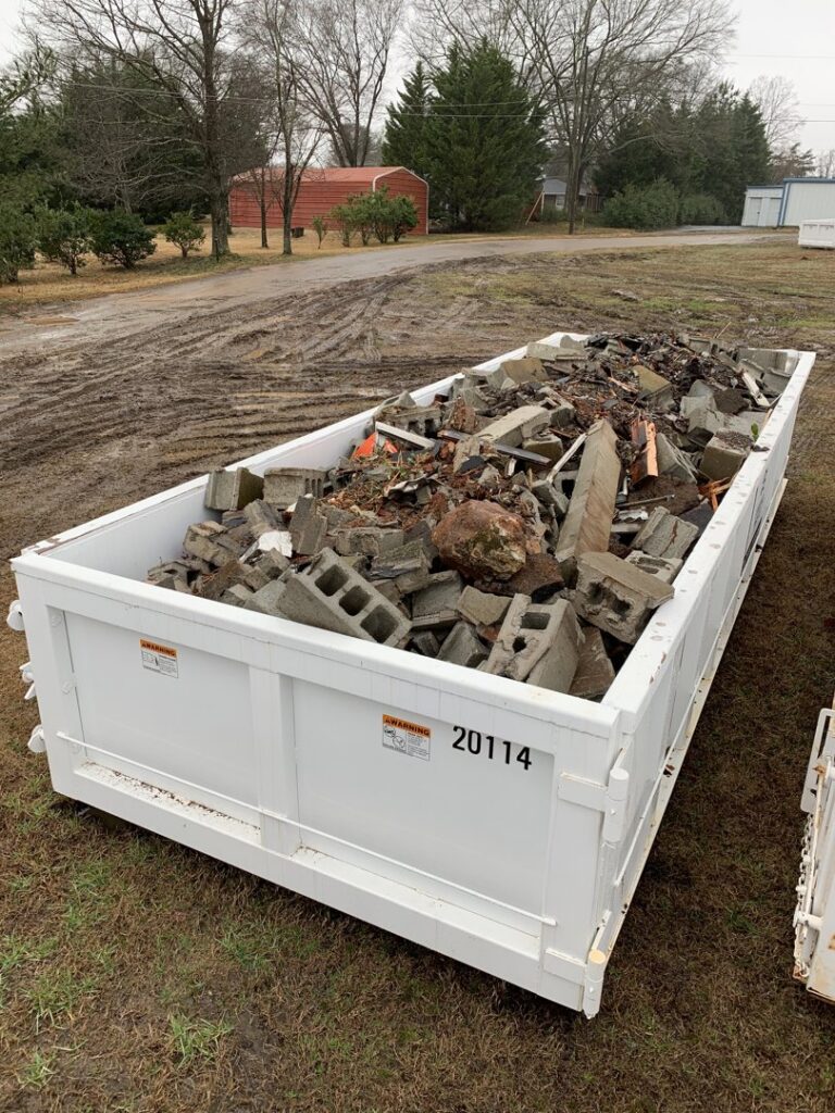 A dumpster filled with concrete blocks and various construction debris, managed by Standard Waste Enterprises in Greenville, SC.