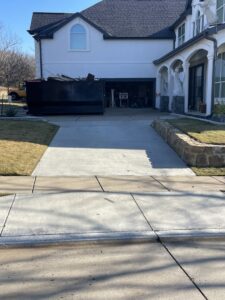 A large dumpster filled with debris parked in front of a residential home by JB'S Junk Removal in Justin, TX.