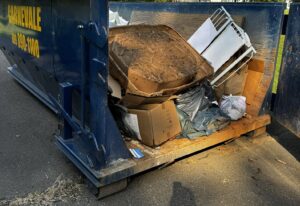 An AJ Carnevale Disposal dumpster filled with general junk and debris, ready for removal in Hamilton, NJ