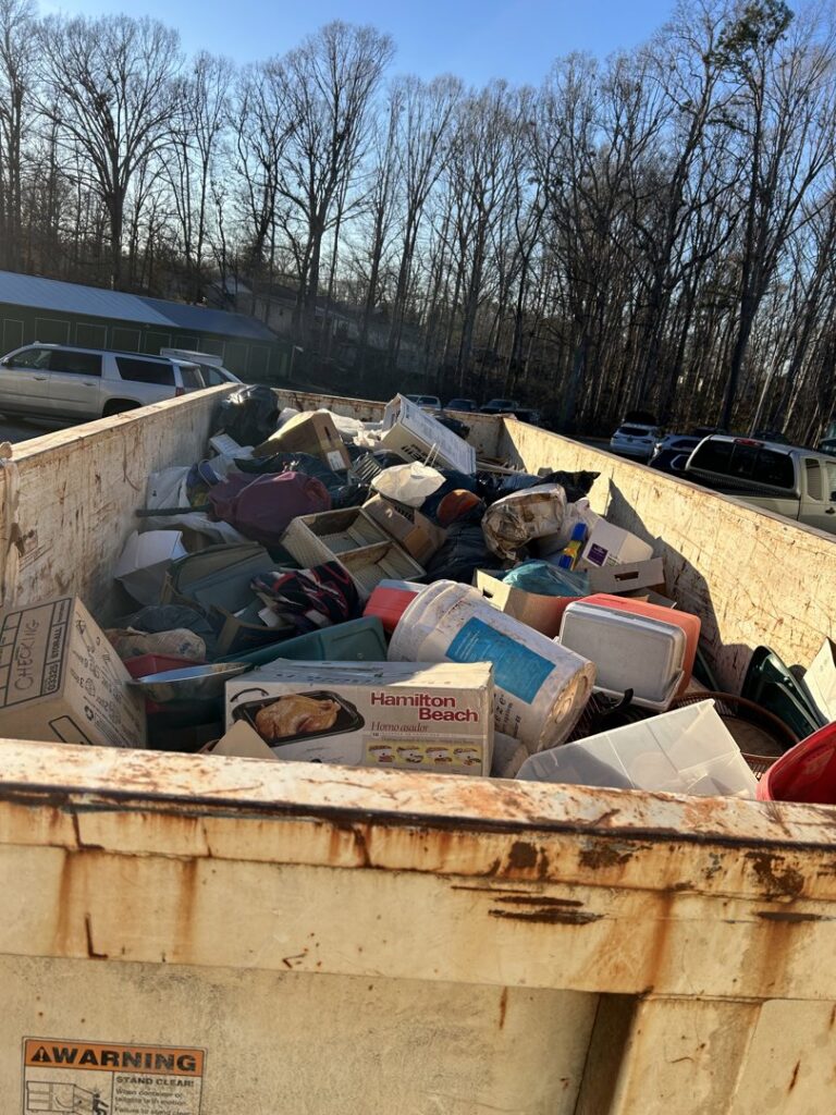 A dumpster filled with various household junk and debris, collected by Standard Waste Enterprises in Greenville, SC.