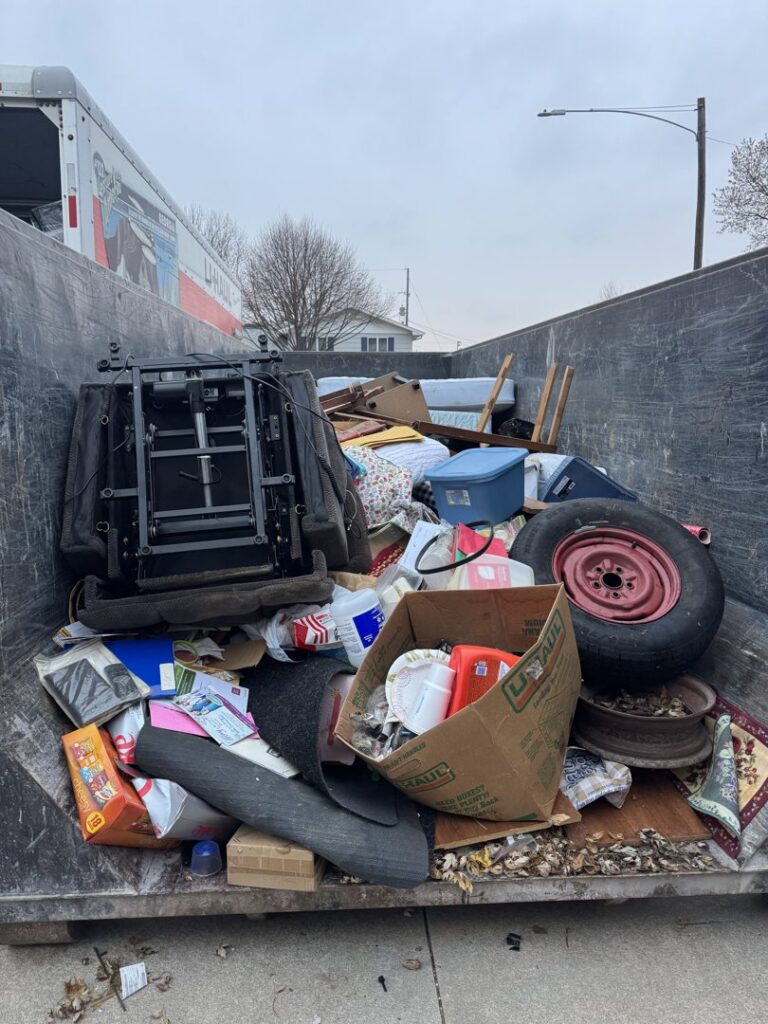 A large dumpster filled with household junk and debris for removal by Clean Slate Removal in Grand Island, NE.