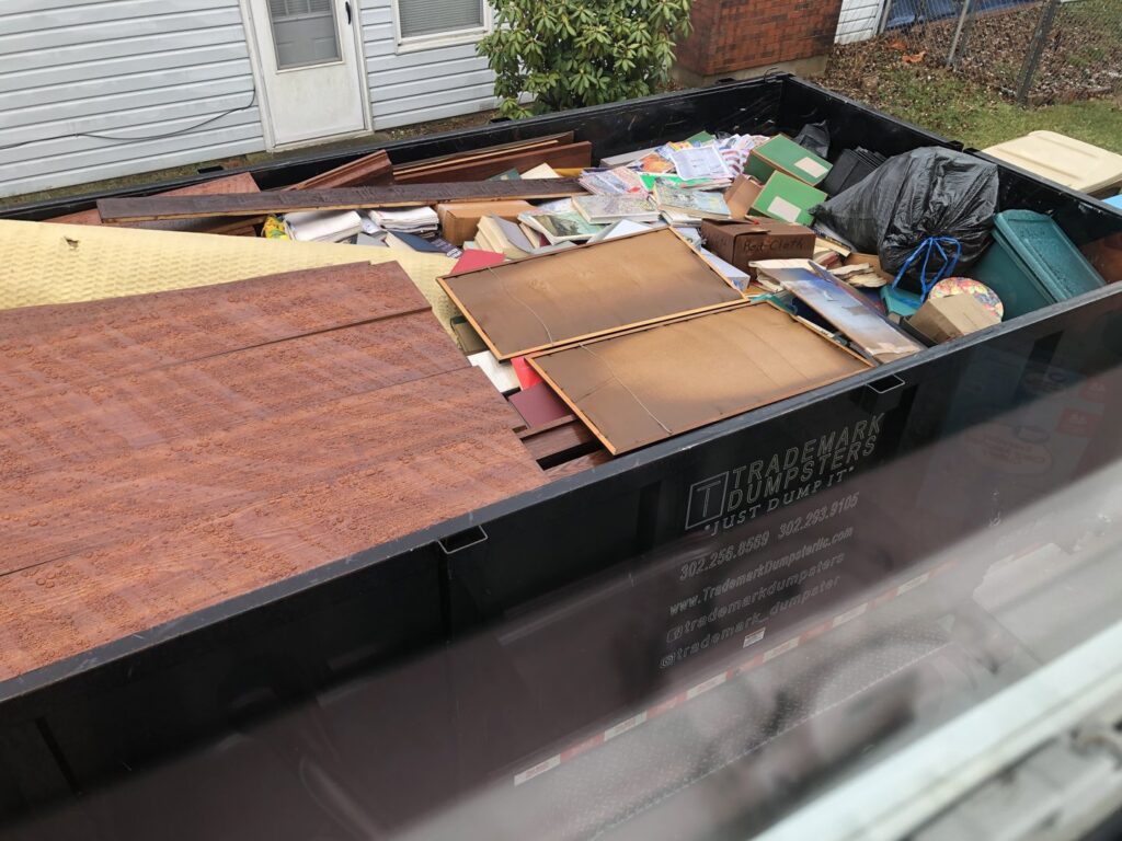 A Trademark Dumpsters trailer filled with household junk, including books and carpet, for removal in Wilmington, DE.