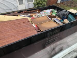 A Trademark Dumpsters trailer filled with household junk, including books and carpet, for removal in Wilmington, DE.