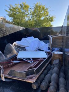 An open dumpster trailer filled with various household junk and debris, demonstrating a junk removal service by Southwestern Dumpster Rental and Junk Removal in Peoria, AZ.