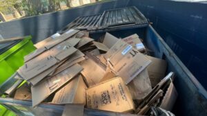 A large blue dumpster filled with cardboard boxes, ready for hauling by Elite Junk Haulers in Pine Bluff, AR.
