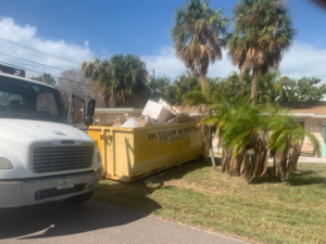 A Big Yellow Dumpster full of construction debris next to a residential house in Saint Petersburg, FL, for a general contractor job.