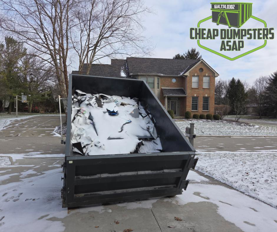 A dumpster full of construction debris in front of a residential home for junk removal by Cheap Dumpsters ASAP in Columbus, OH.