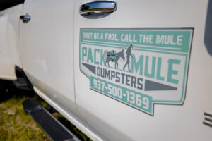 A large green dumpster overflowing with household junk and debris, demonstrating general junk removal by Pack Mule Dumpsters Dayton, OH.