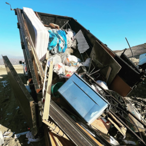A large dumpster overflowing with various junk and debris, ready for removal by Frontier Dumpster Rentals in Cheyenne, WY.