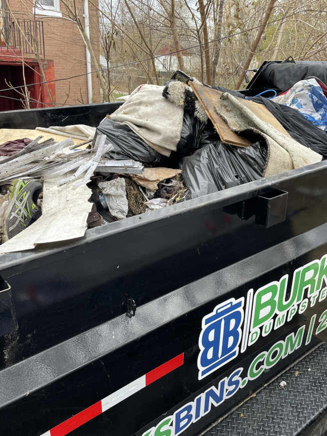 A large dumpster filled with various household junk and construction debris, collected by Lion's Pride Trash Removal Services in Hammond, IN.