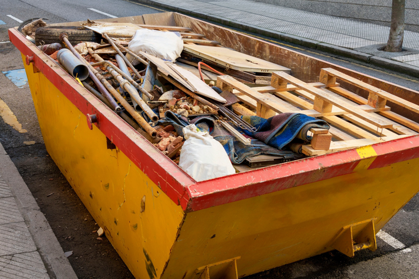 A large yellow dumpster filled with construction debris and household junk, ready for removal by Waste Away Now Inc. in Charlotte, NC.