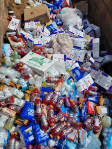 A large dumpster filled with mixed junk and discarded products, handled by Jugganott Recycling, LLC in Orlando, FL.