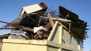 A large yellow dumpster overflowing with scrap metal, old appliances, and various junk collected by Junk in the Truck LLC in Albuquerque, NM.