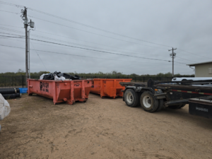 A Rush Disposal LLC dumpster filled with trash bags and debris from a general junk removal service in Laredo, TX.