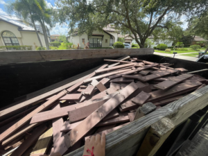 A dumpster trailer filled with old wood planks and decking material for junk removal by Trash N Go Dumpster's in Orlando, FL.