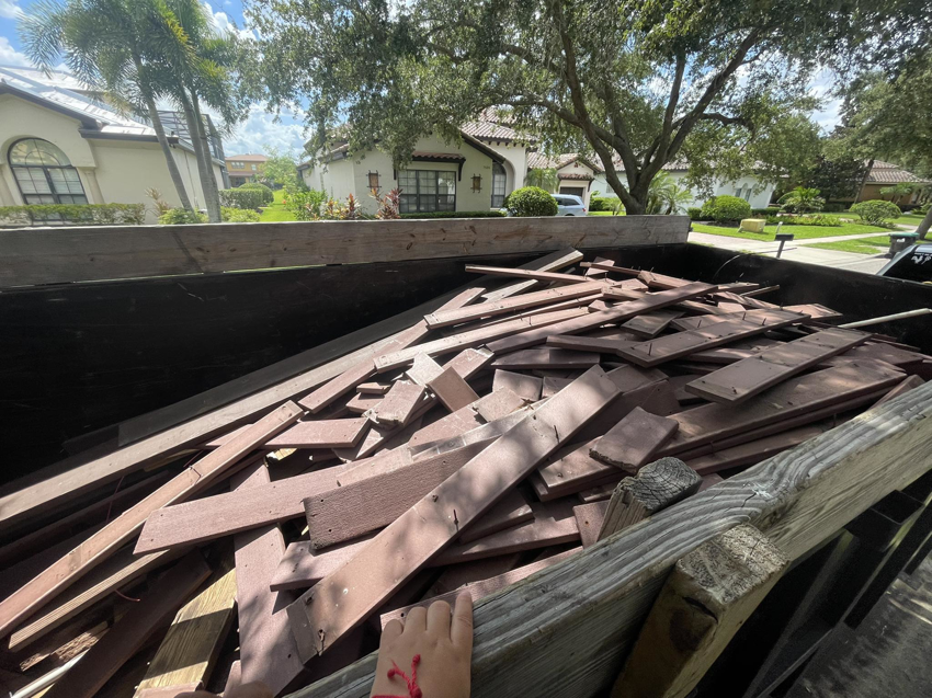 A dumpster trailer filled with old wood planks and decking material for junk removal by Trash N Go Dumpster's in Orlando, FL.