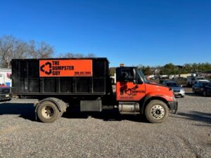 A branded roll-off truck from The Dumpster Guy, ready for junk removal services in Webster, MA.