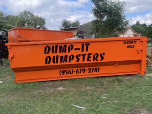 An orange Dump-IT Dumpster Rentals LLC dumpster placed in a backyard in Laredo, TX, ready for a junk removal project.