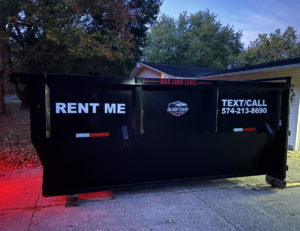 A Dump that Junk LLC dumpster placed in a residential driveway at dusk in Mishawaka, IN.