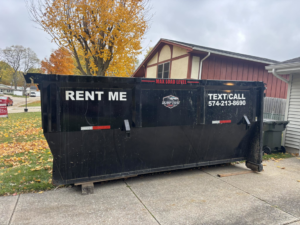 A Dump that Junk LLC dumpster placed in a driveway with autumn leaves on the ground in Mishawaka, IN.