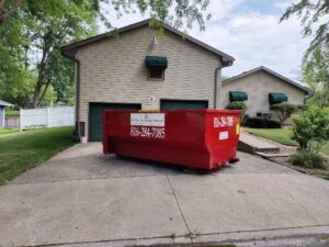 A red dumpster from Trinity Dumpster Rental LLC placed in a residential driveway in Kansas City, MO.