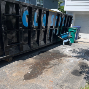 A large Classic Disposal dumpster placed in a residential driveway for junk removal in Malden, MA.