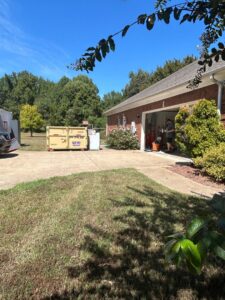 A dumpster from Curry Dumpster Rentals LLC placed in a residential setting for junk removal services in Southaven, MS.