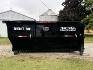 A Dump that Junk LLC dumpster placed in a rural setting with a silo in the background in Mishawaka, IN.