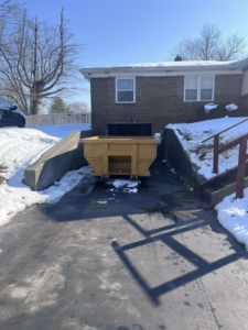 A Speedy Dumpsters roll-off container positioned in a snowy residential driveway in Brownsburg, IN.