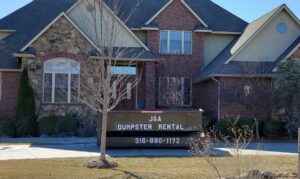 A J & A Haul Away & Dumpster Rentals black dumpster placed in front of a large residential home in Derby, KS.
