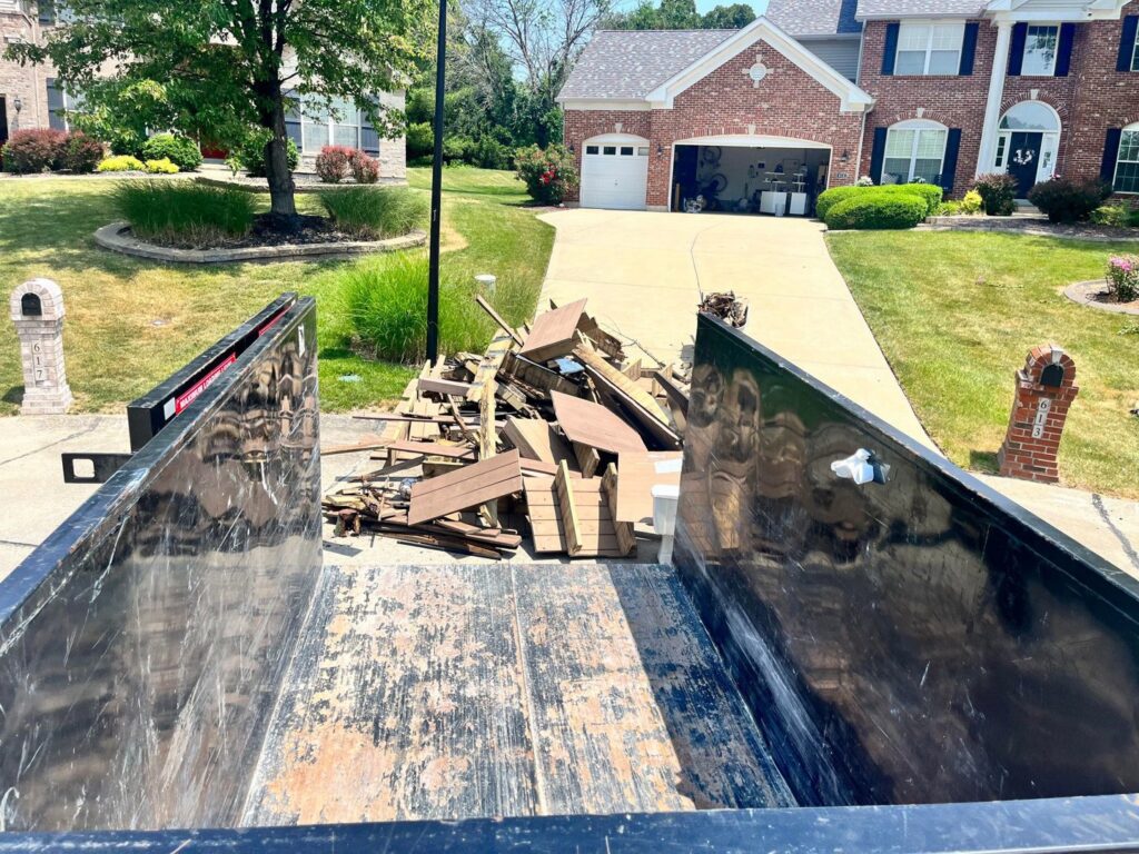 A Buzz Dumpster & Junk Removal container being loaded with debris during a junk removal service in Troy, MO.