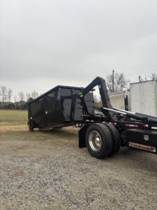 A Wallburg Disposal Worx LLC truck loading or unloading a black dumpster in High Point, NC.
