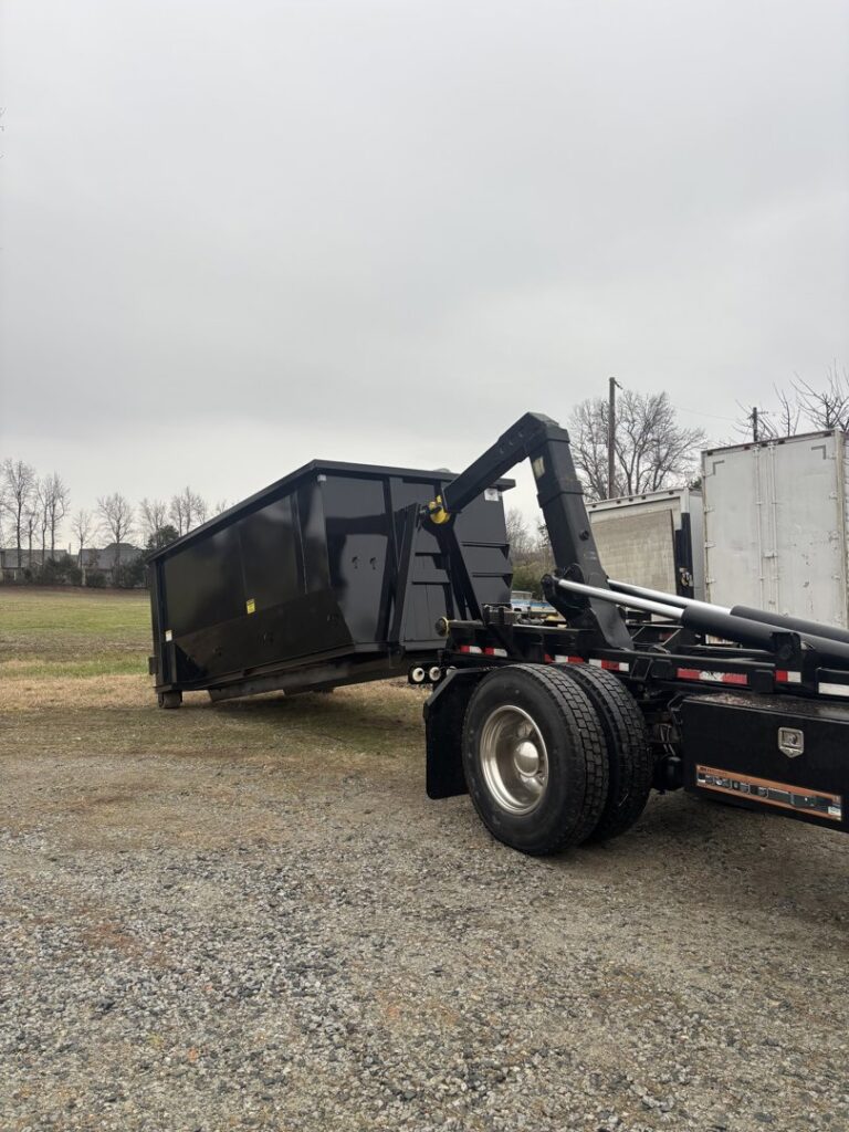 A Wallburg Disposal Worx LLC truck loading or unloading a black dumpster in High Point, NC.