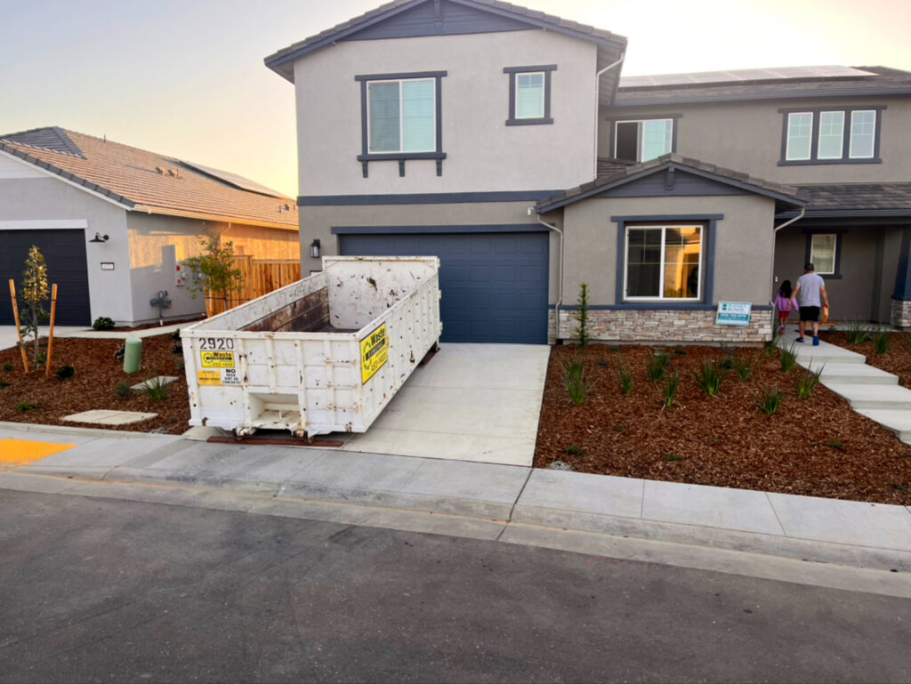 A roll-off dumpster placed in front of a new residential home for waste removal by Waste Removal and Recycling, Inc. in Sacramento, CA.