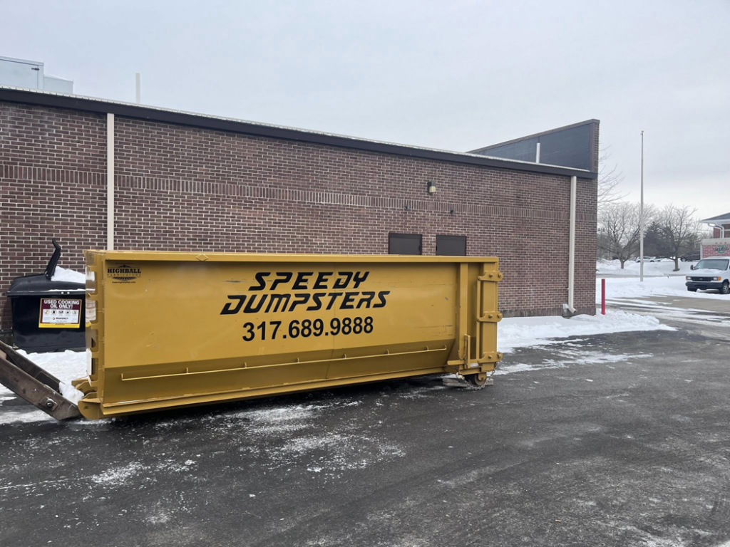 A Speedy Dumpsters roll-off container next to a brick commercial building in Brownsburg, IN.
