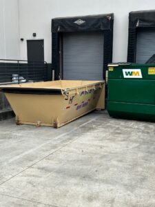 A dumpster from Curry Dumpster Rentals LLC placed next to a large commercial waste bin for junk removal in Southaven, MS.