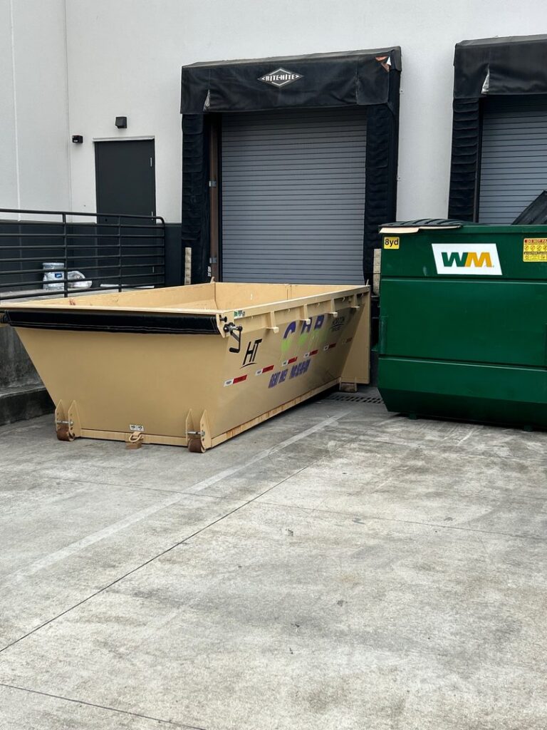 A dumpster from Curry Dumpster Rentals LLC placed next to a large commercial waste bin for junk removal in Southaven, MS.