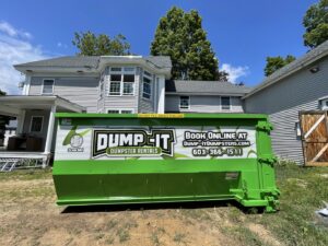 A green Dump-It Dumpster Rentals dumpster placed next to a house undergoing renovation in Concord, NH.