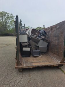 A large dumpster filled with office chairs and furniture for removal by Remove Recycle Remarket in Troy, MI.