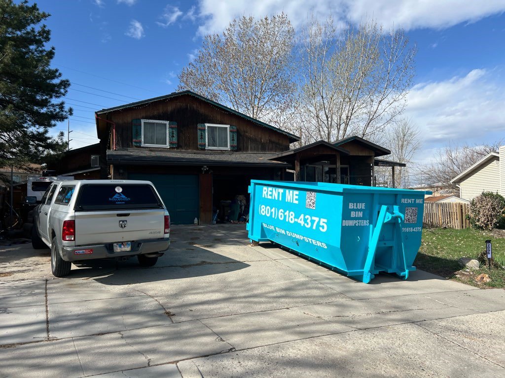 A blue dumpster placed on a residential driveway, ready for junk removal by Blue Bin Dumpster Rentals in Salt Lake City, UT.