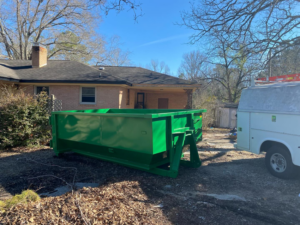 A green dumpster from Dumpster on Demand positioned on a residential driveway for a home cleanup in Columbia, SC.