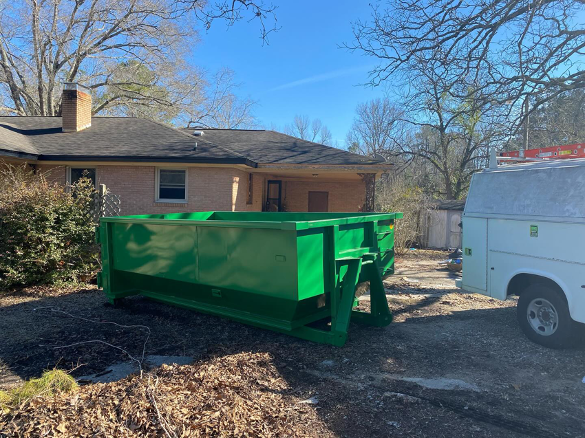 A green dumpster from Dumpster on Demand positioned on a residential driveway for a home cleanup in Columbia, SC.