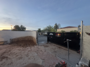 A large black dumpster placed on a paved driveway, ready for junk removal services by M&O Dumpster Services in Tolleson, AZ.
