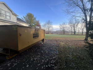 A Speedy Dumpsters roll-off container on a driveway with fallen leaves in Brownsburg, IN.