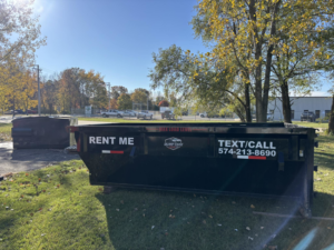 A Dump that Junk LLC dumpster placed on a grassy area near a commercial setting in Mishawaka, IN.